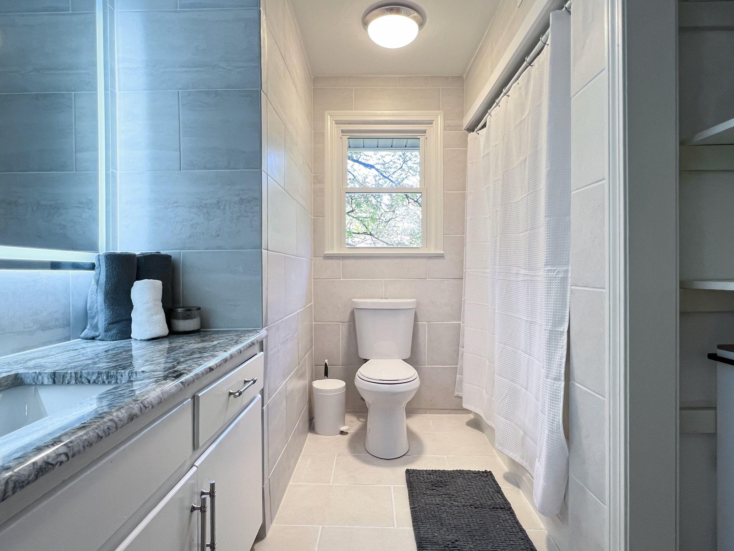 New floor to ceiling tile, granite countertop, and modern mirror transform bathroom